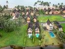 Aerial view of beachfront properties with gardens, swimming pools, and lush greenery