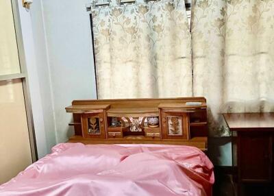 Bedroom with pink bedspread and wooden furniture