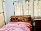 Bedroom with pink bedspread and wooden furniture