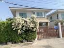 Two-story house with a gated entrance and blooming flowers