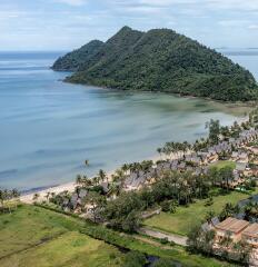 Aerial view of beachfront resort with mountain backdrop