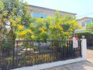 A residential building with yellow flowering plants in the front yard