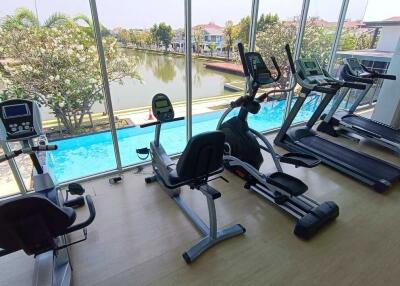 Well-equipped gym with cardio machines overlooking a pool and scenic outdoor view