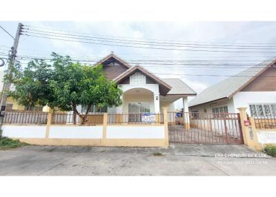 Front view of a single-story house with a fence and a tree