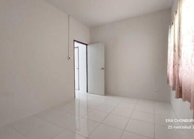 Empty bedroom with white tiles and a door leading to another room