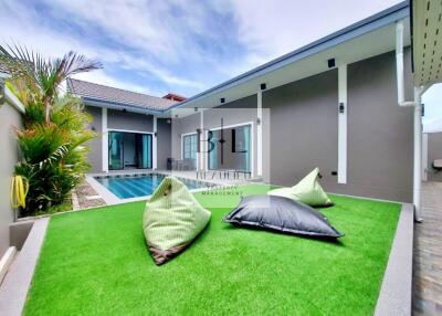 Modern outdoor space with artificial grass, bean bags, and swimming pool