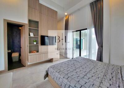 Modern bedroom with built-in wooden closet, wall-mounted TV, and large windows with curtains