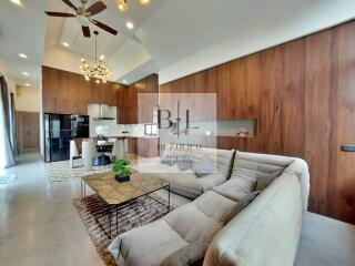 Modern living room with open kitchen, high ceiling, and ceiling fan