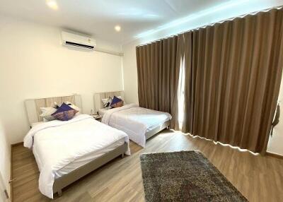 A modern bedroom with two beds and brown curtains