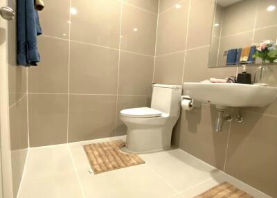 Modern bathroom with tiled walls and floor, featuring a sink and toilet