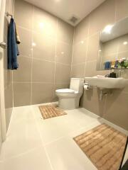 Modern bathroom with tiled walls and floor, featuring a sink and toilet