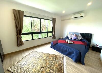 Spacious bedroom with a large window, wooden flooring, and a double bed