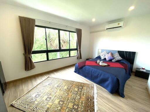 Spacious bedroom with a large window, wooden flooring, and a double bed