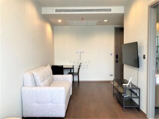 Modern living room with white couch, wall-mounted TV, and a small desk