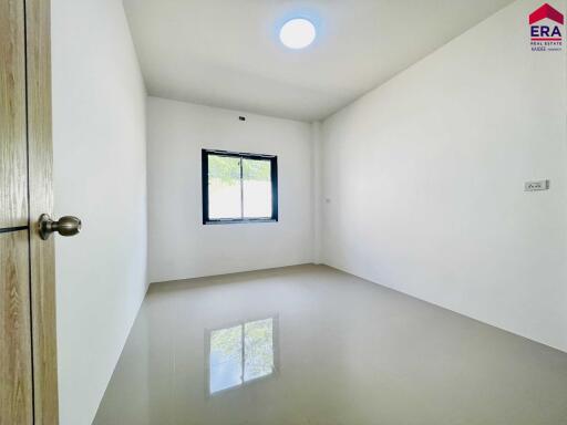 Empty bedroom with a single window and tiled floor