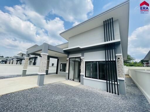 Modern single-story house exterior with driveway and gravel front yard