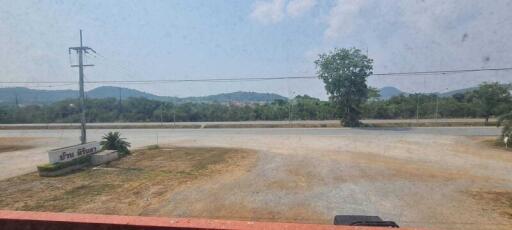 View from the property showing a road, open space, and distant hills