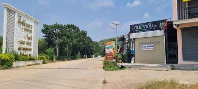 Street view of commercial buildings with signage and greenery