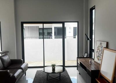 Modern living room with a leather sofa, coffee table, and large windows