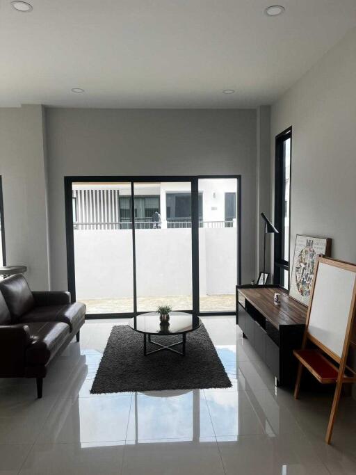 Modern living room with a leather sofa, coffee table, and large windows