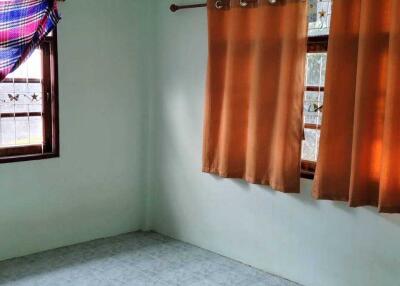 Empty bedroom with tiled floor and curtains on windows