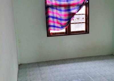 Empty bedroom with a tiled floor and a window covered by a plaid cloth.