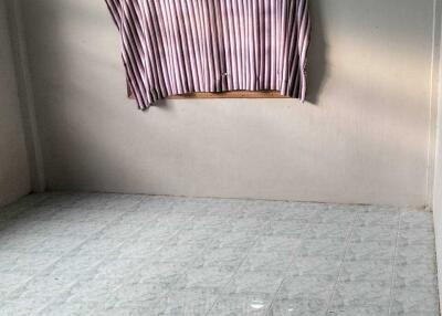 Empty room with tiled flooring and a window covered by striped curtains