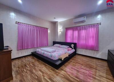 Bedroom with wooden flooring, pink curtains, and a platform bed