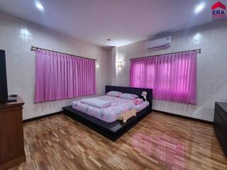 Bedroom with wooden flooring, pink curtains, and a platform bed