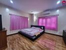 Bedroom with wooden flooring, pink curtains, and a platform bed
