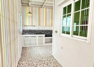 Bright kitchen with modern design including striped walls, white cabinets, tiled backsplash, and a large window