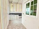 Bright kitchen with modern design including striped walls, white cabinets, tiled backsplash, and a large window