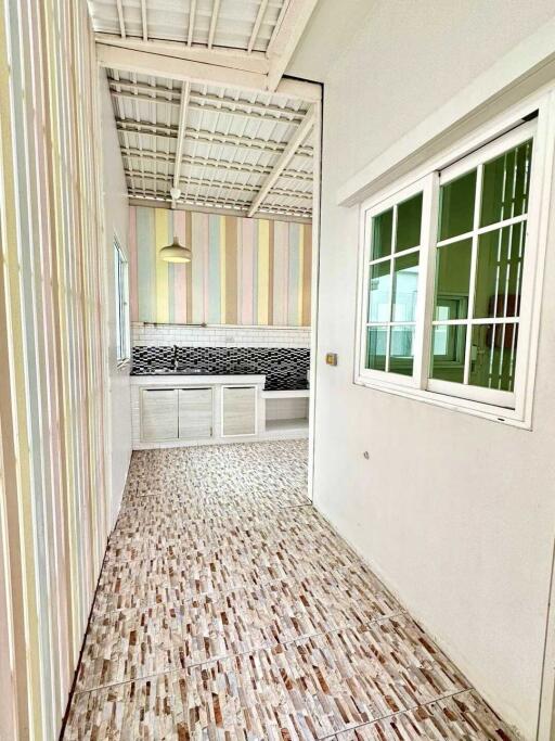 Bright kitchen with modern design including striped walls, white cabinets, tiled backsplash, and a large window