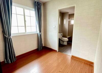 Bedroom with attached bathroom featuring a window and wooden flooring