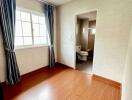 Bedroom with attached bathroom featuring a window and wooden flooring