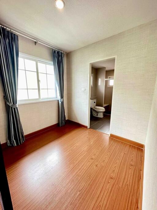 Bedroom with attached bathroom featuring a window and wooden flooring