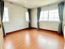 Bright and spacious bedroom with wooden flooring and large windows.