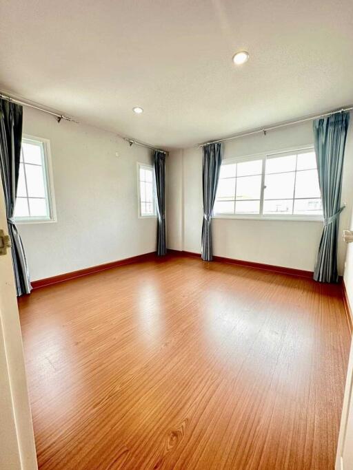 Bright and spacious bedroom with wooden flooring and large windows.