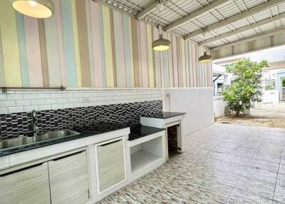 Covered outdoor kitchen with tiled flooring and wall