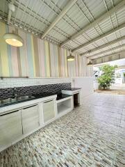 Covered outdoor kitchen with tiled flooring and wall