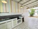 Covered outdoor kitchen with tiled flooring and wall