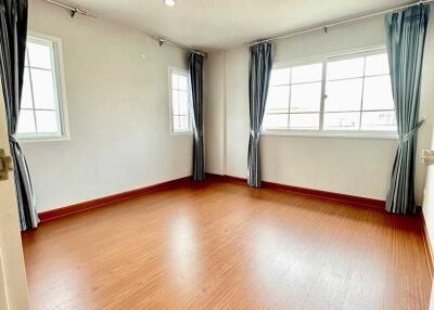 Spacious bedroom with wooden floor and large windows