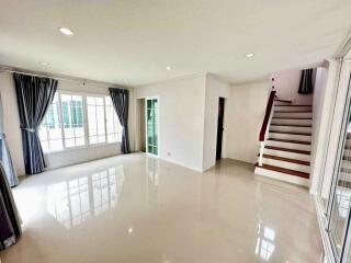 Spacious living room with large windows and stairs