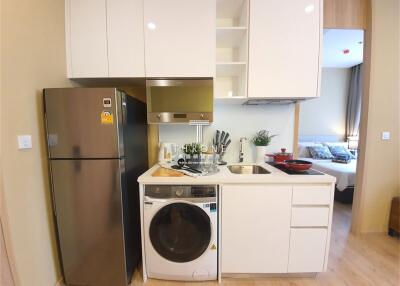 Modern kitchen with integrated stove and sink, fridge, and laundry machine