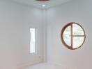 Minimalist white room with round window and tall narrow window