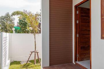 Exterior view of the house entrance with wooden door and small garden