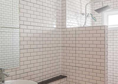 Modern white-tiled bathroom with a vessel sink and glass shower