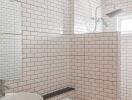 Modern white-tiled bathroom with a vessel sink and glass shower