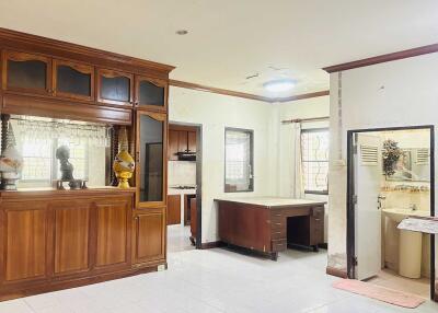 Main living space with wooden cabinets and desk, visible kitchen and bathroom