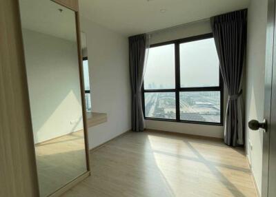 Spacious bedroom with wooden flooring and large windows